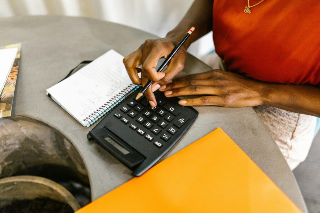 pexels-photo-7491011-7491011 An African American woman using a calculator and notepad for budgeting.